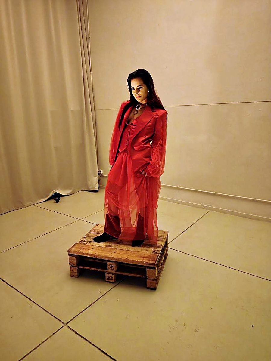 Modelo em fato Flame Scarlet com tule, sobre plinto de madeira, luz vermelha