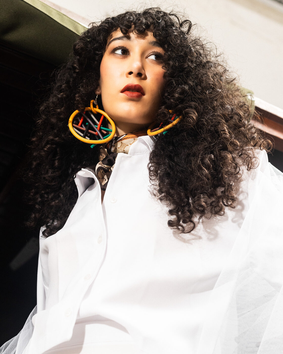 Retrato de modelo em camisa Bright White com lenço estampado e brincos de argola coloridos