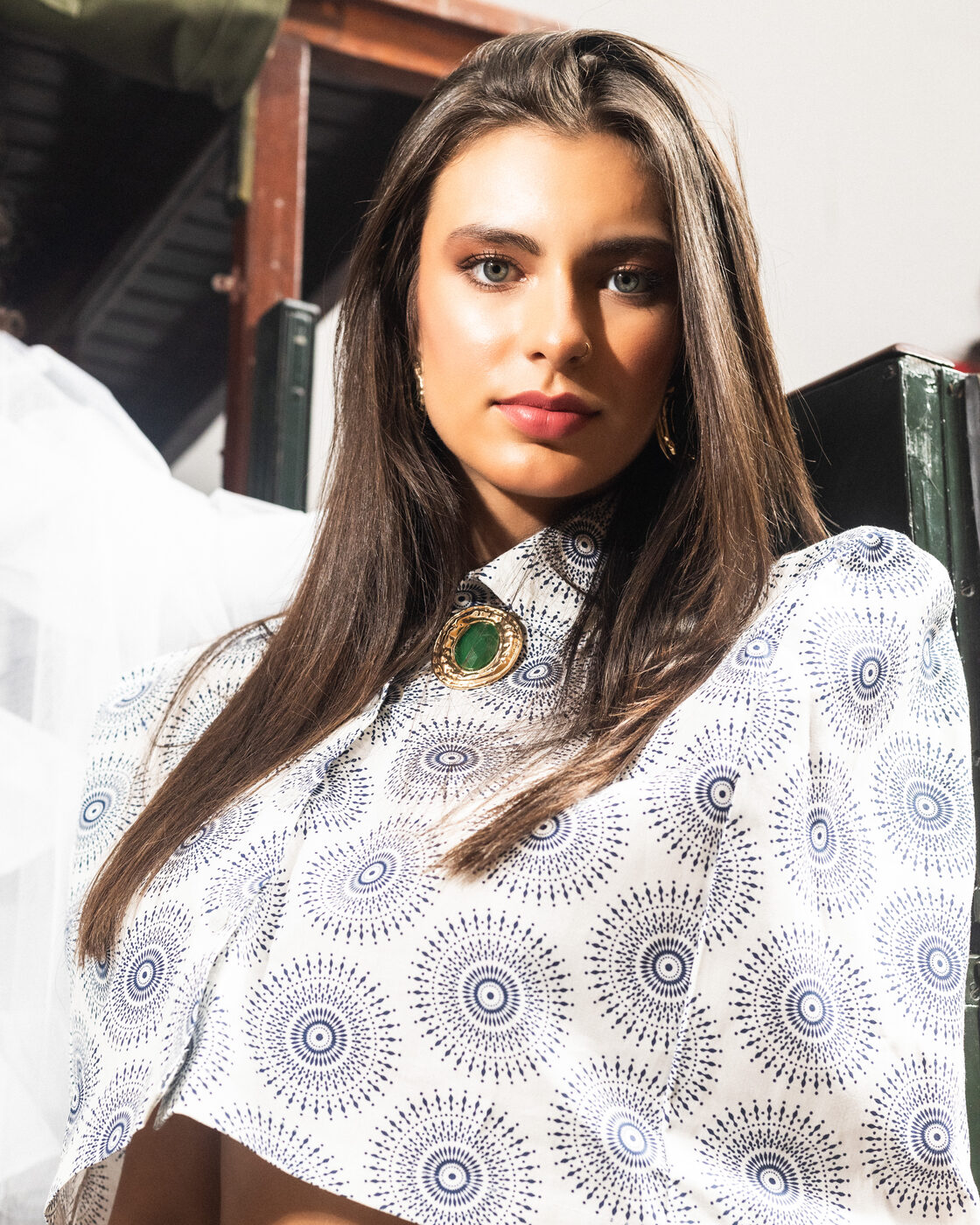 Retrato de modelo em conjunto estampado de círculos com broche de pedra verde