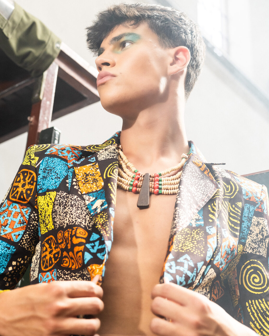 Retrato de modelo em blazer estampado aberto com colar de contas e maquilhagem verde
