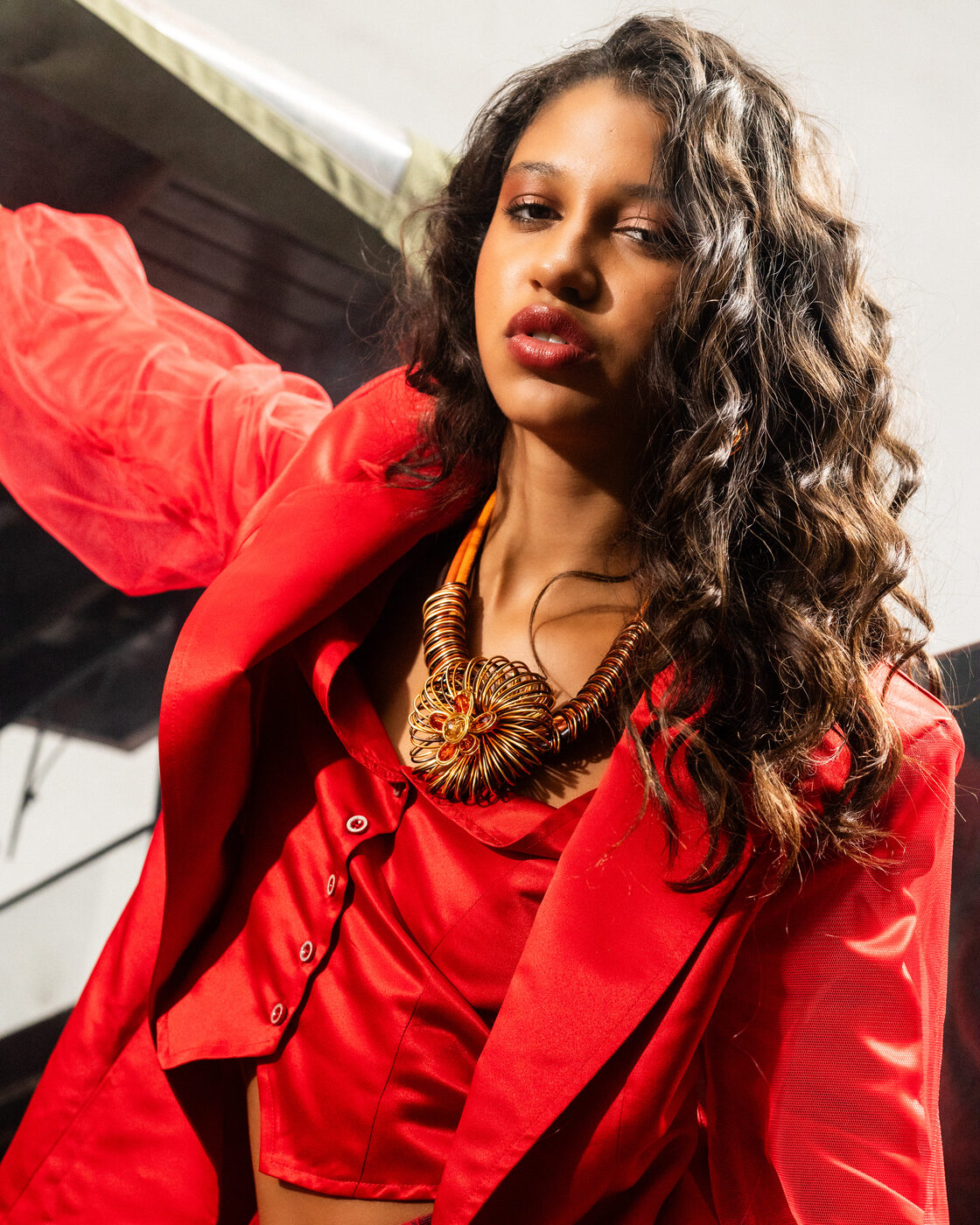 Retrato de modelo em look Flame Scarlet de cetim com colar-statement dourado